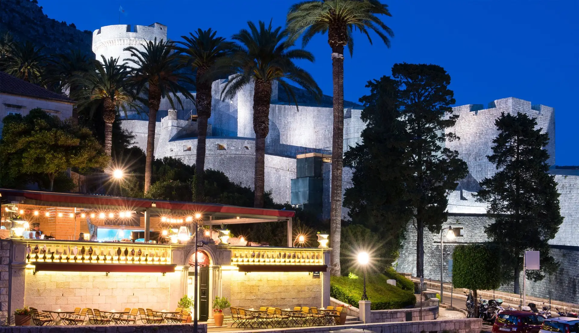 medival fortess with walls surounded by palm trees ond building in front
