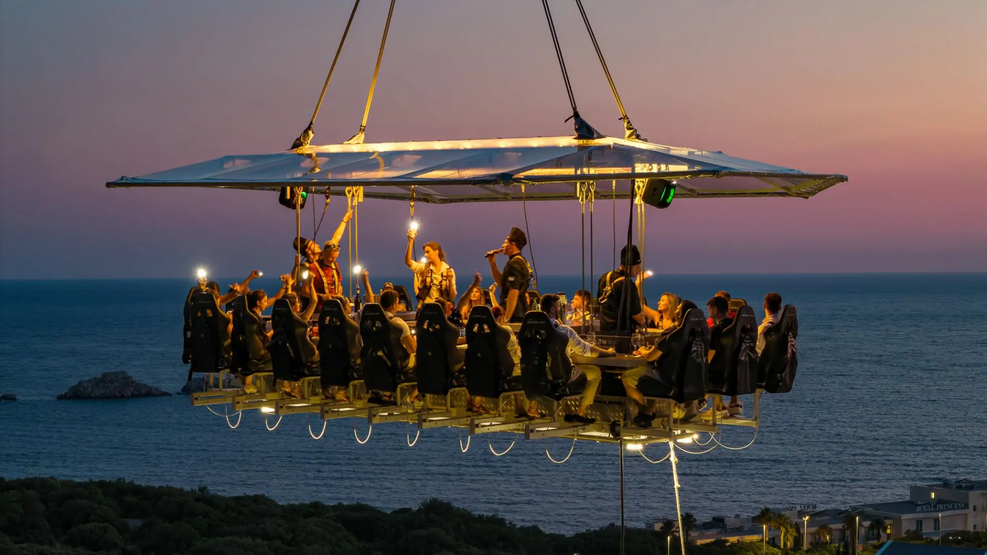 People having dinner in they sky with the sea bellow them