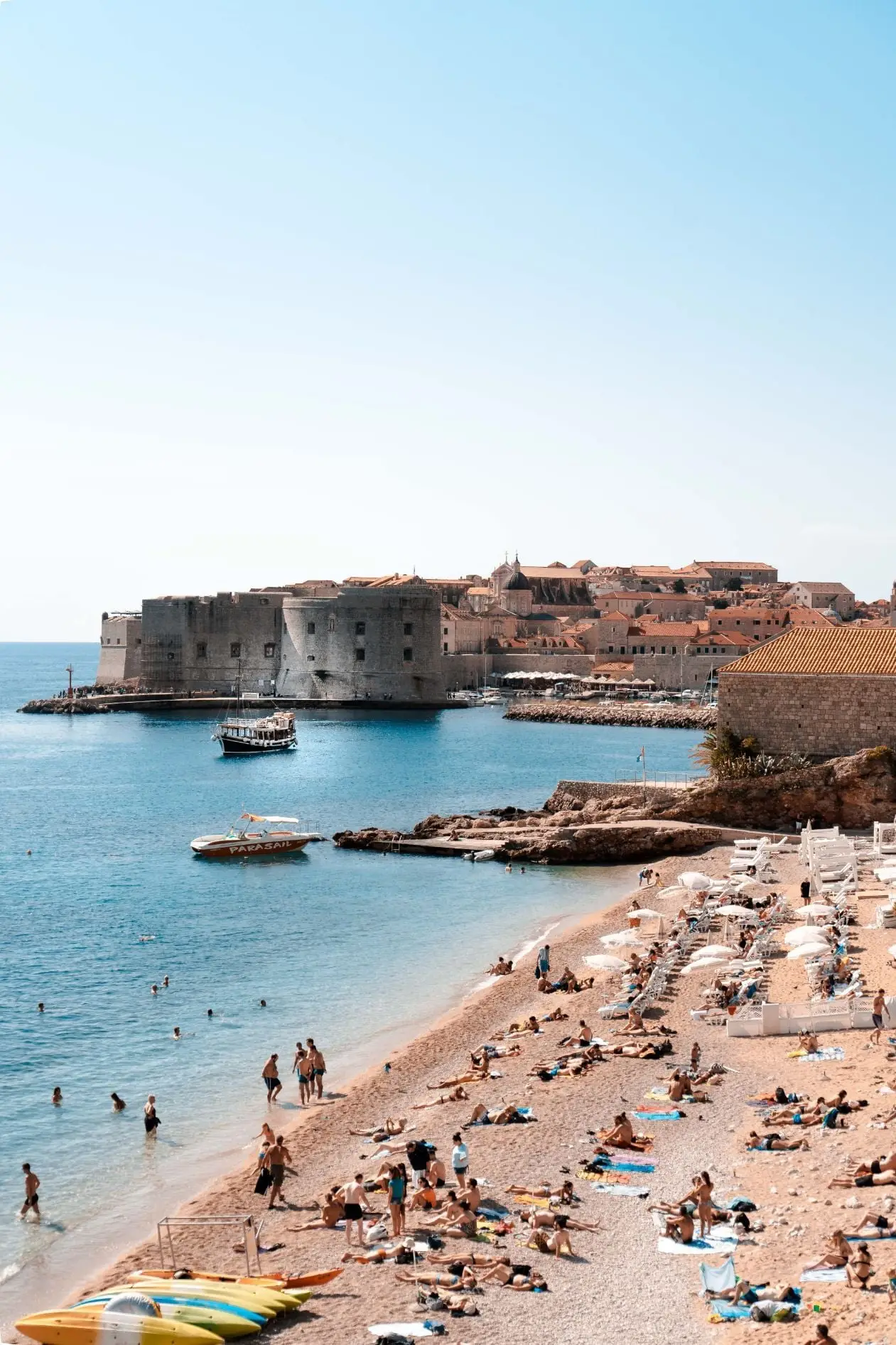 people at the beach with the old town behind