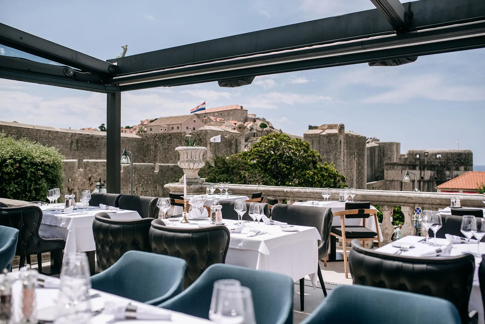 terrace of a restaurant with tables and chairs and city behind 