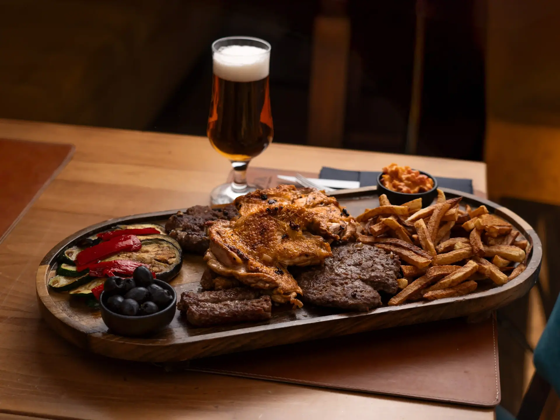 meat, fries and vegetables on a plet with a glass of beer